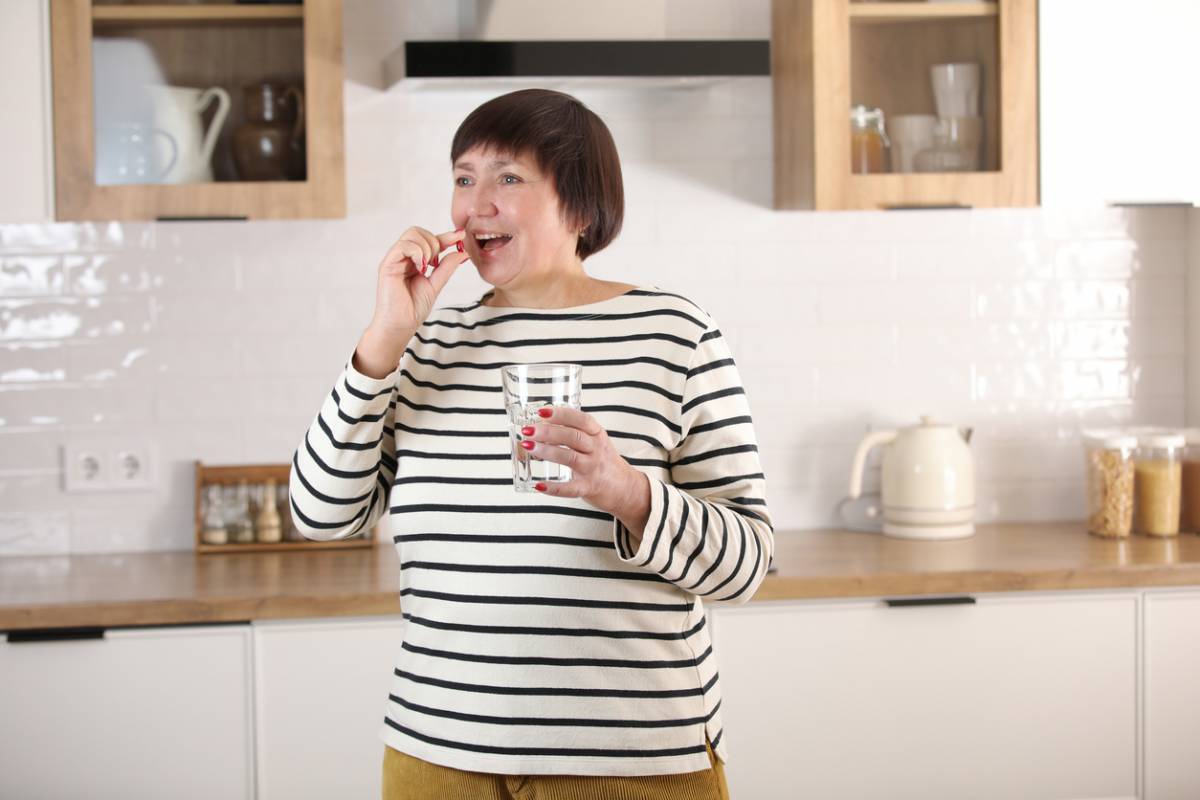 femme avale comprimé avec verre eau