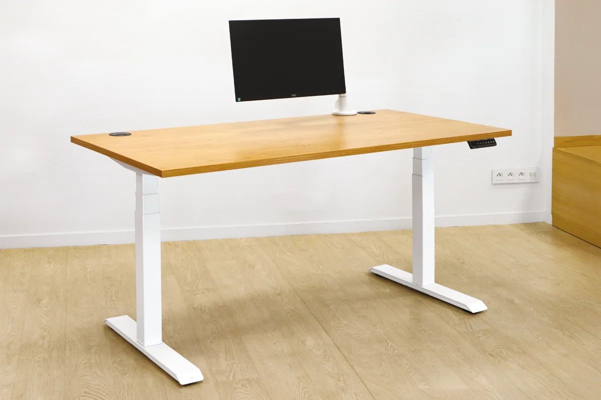 Bureau assis-debout électrique avec écran sur bras articulé dans un bureau lumineux
